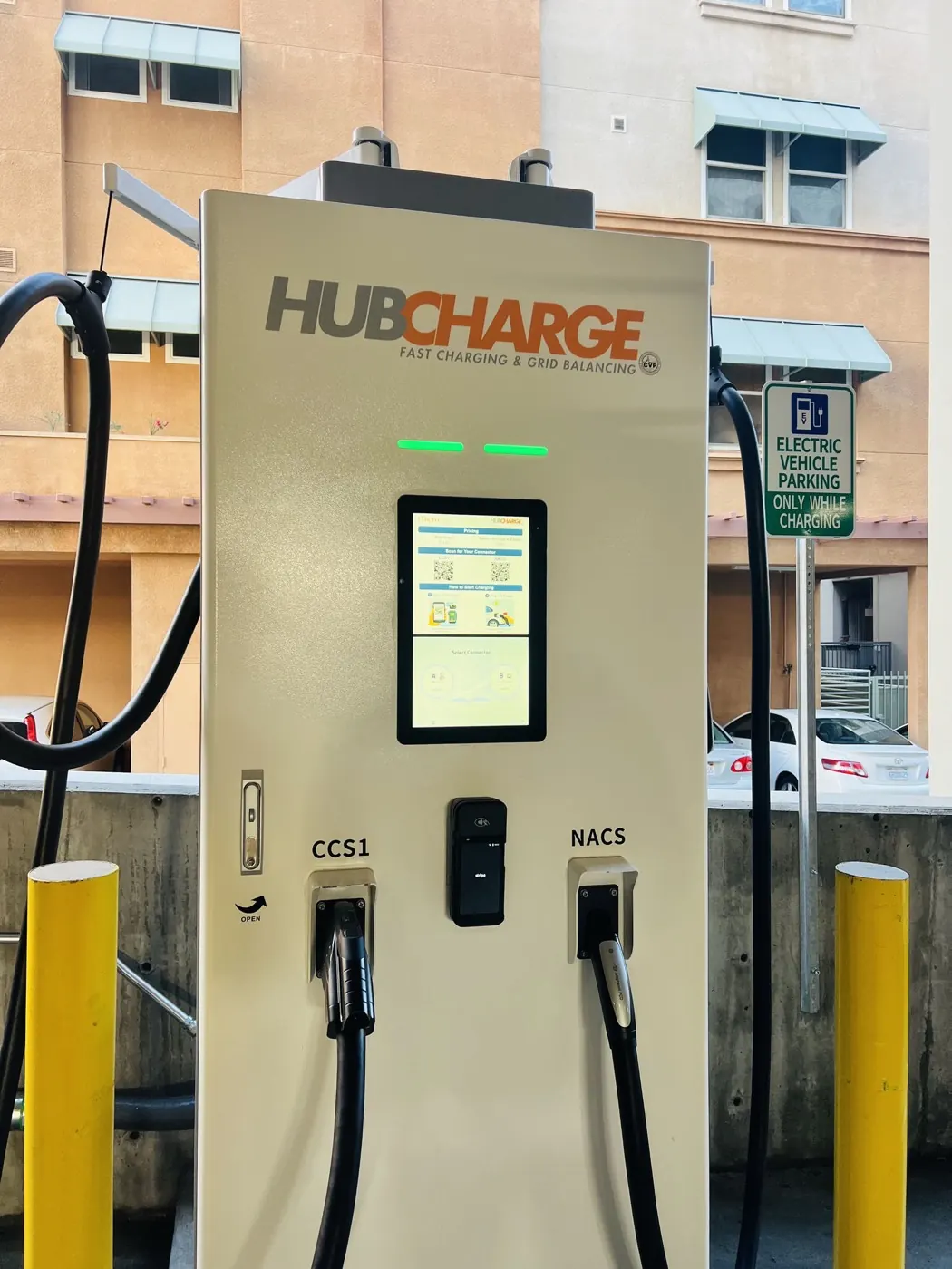 The HubCharge unit at Alhambra showing pricing and connector QR codes on its screen, with CCS1 and NACS cables holstered